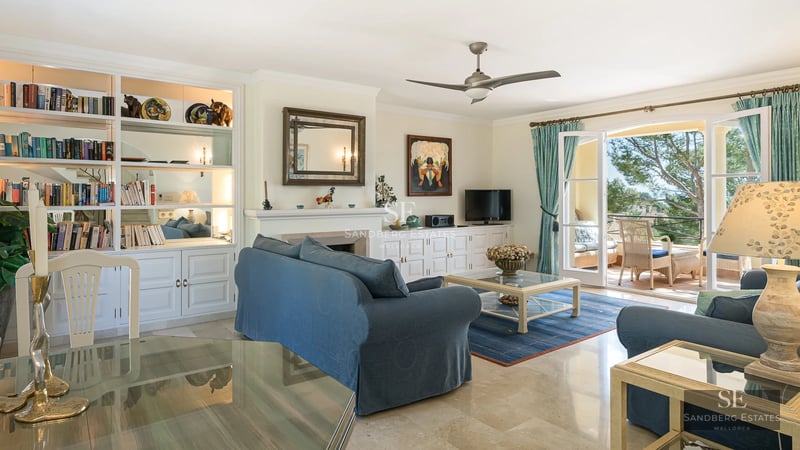 Exterior view of a modern villa with a pool, lush garden, and large windows reflecting sunlight.