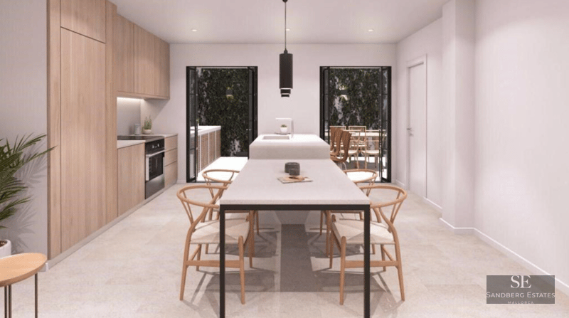 Modern kitchen with light wood cabinets, white central island, and integrated dining table with wooden chairs.