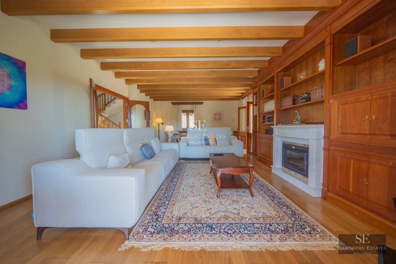 Spacious living room with panoramic sea view windows. Modern design, light wood floors, beige sofas, and blue accents. Abundant natural light.