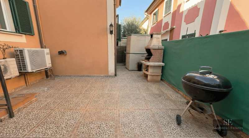 Outdoor patio with stone-patterned tiles, a masonry BBQ, a portable kettle grill, and a green privacy screen.