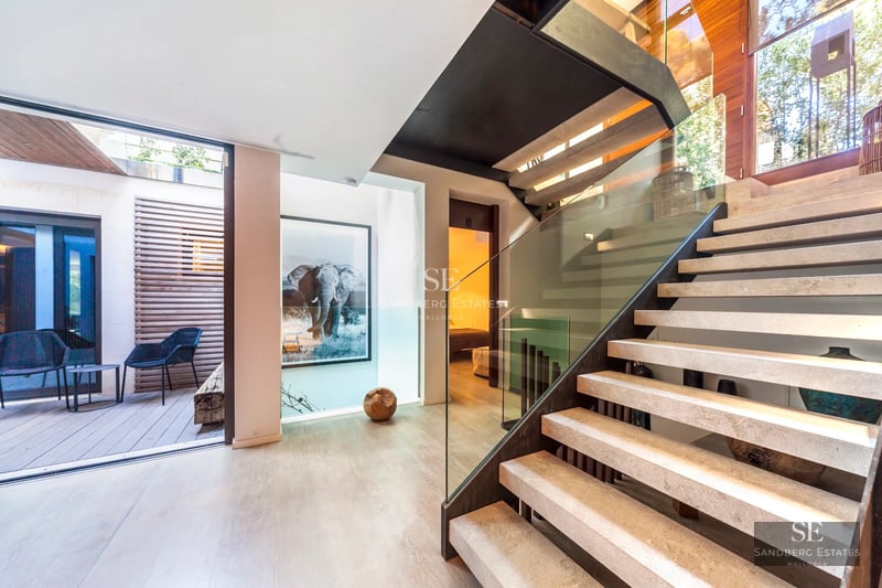 View of a modern villa with infinity pool and lush garden. Minimalist architecture with large windows and high-end materials.