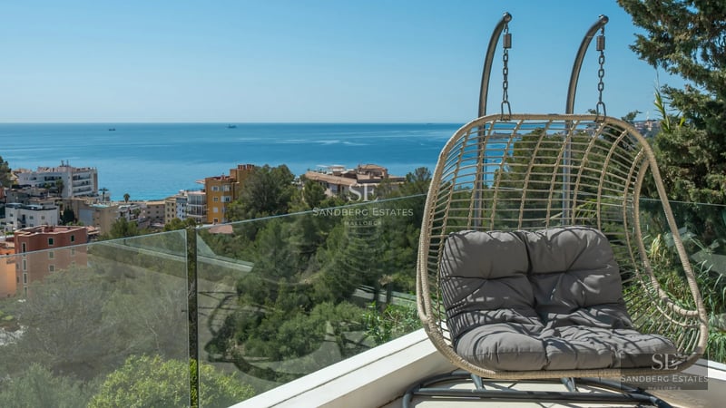 Spacious living room with floor-to-ceiling windows, wood floors, fireplace, and sea view. Modern and elegant furniture. Natural light.