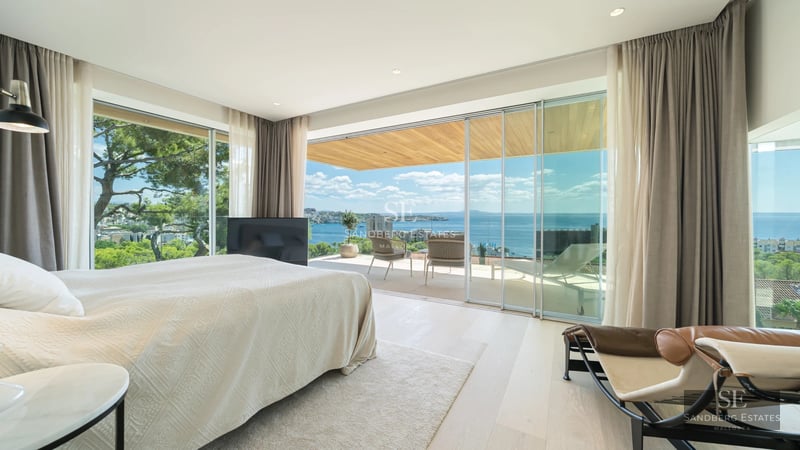 Spacious living room with a modern fireplace and large windows overlooking the lush garden. Elegant furniture and design details.