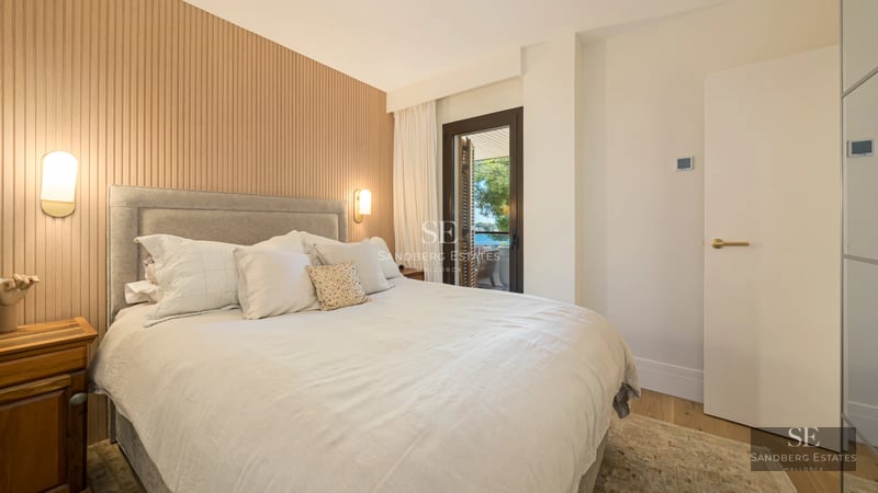 View of a luxurious pool with loungers and umbrellas, surrounded by a manicured garden. Modern and elegant architecture.