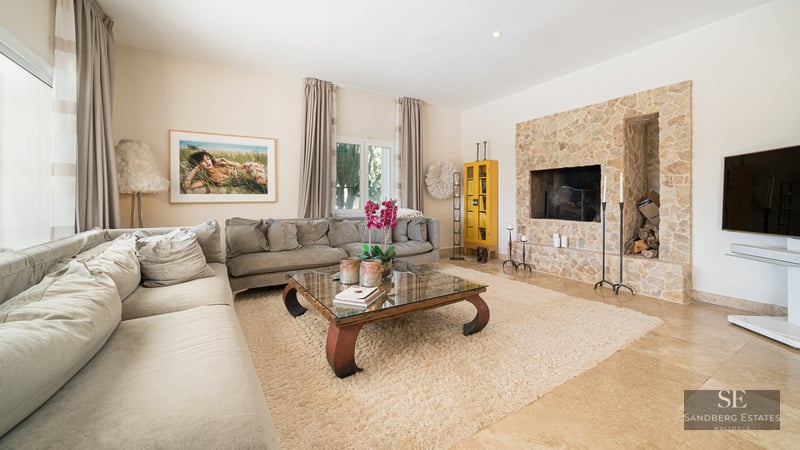 Spacious living room featuring a large grey sectional, a natural stone fireplace, and a glass coffee table on a plush rug.