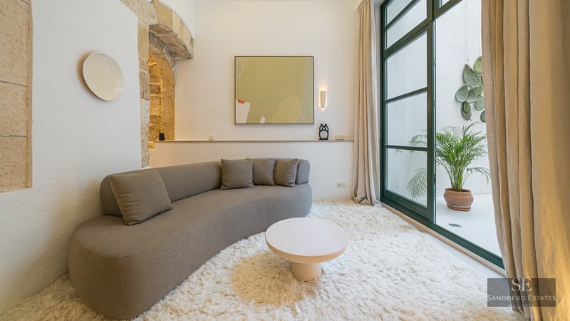 Modern curved sofa on a white shag rug in a room featuring a stone arch and patio access.