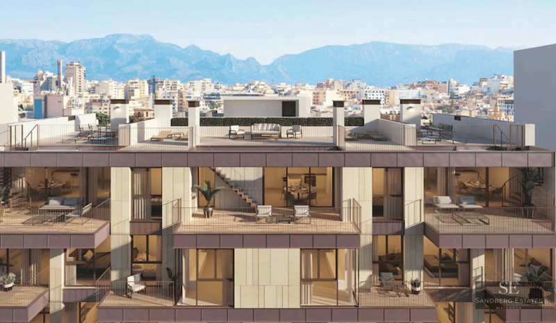Modern building facade featuring multiple balconies, rooftop terraces, and a backdrop of city and mountains.