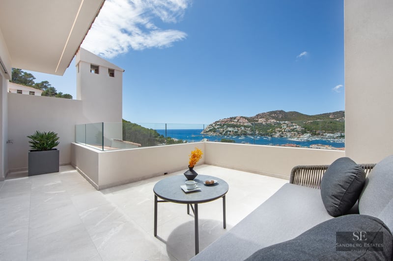 Luxury terrace with glass railings, outdoor sofa, and a breathtaking view of a Mediterranean harbor.