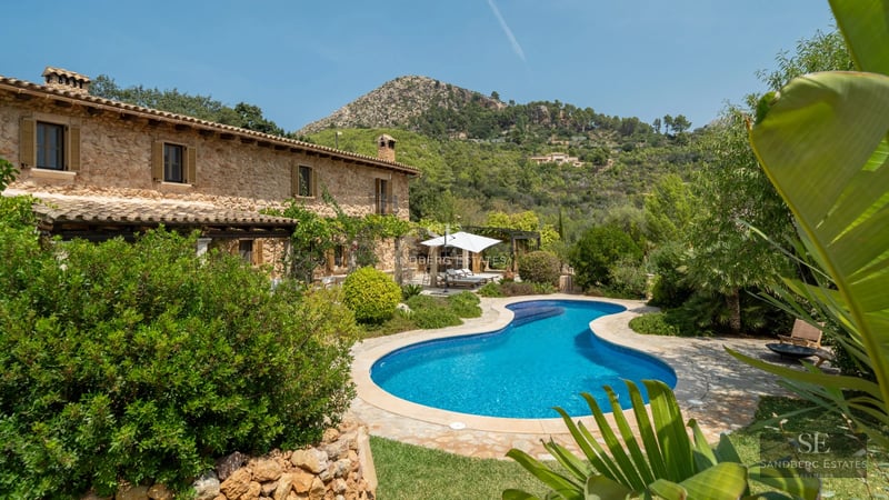 Modern exterior with infinity pool, wooden deck and large windows. Sleek, minimalist design. Green lawn.
