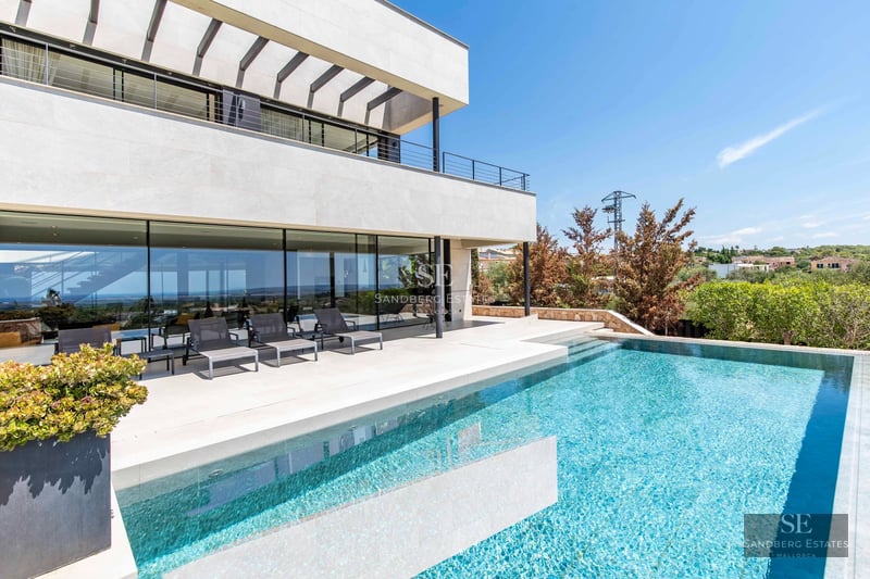 Expansive terrace with infinity pool, sun loungers, and panoramic views. Modern design with high-end finishes and lush greenery.