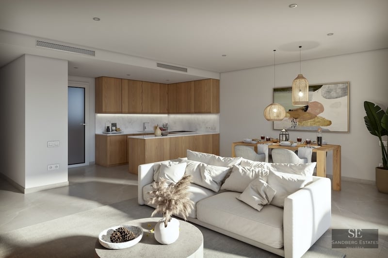 Bright open-plan living space with a white sofa, wooden kitchen cabinets, and a dining area with woven pendant lights.