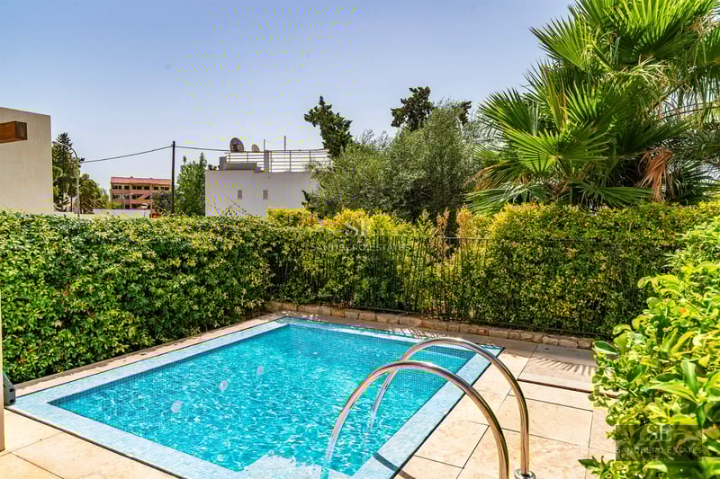 Spacious living room with floor-to-ceiling windows, wood floors, modern fireplace, and stunning views. Grey sofas, glass coffee table. Contemporary design.