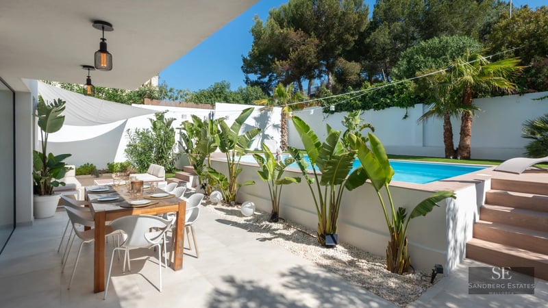 Exterior view of a modern villa with infinity pool, large windows, and lush landscaping. Contemporary architectural design.