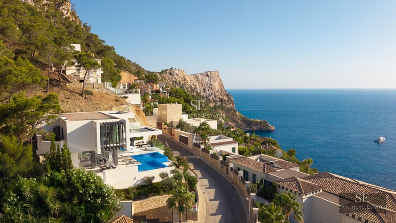Modern living room with large windows, grey sofas, light rug and panoramic sea views. Abundant natural lighting.