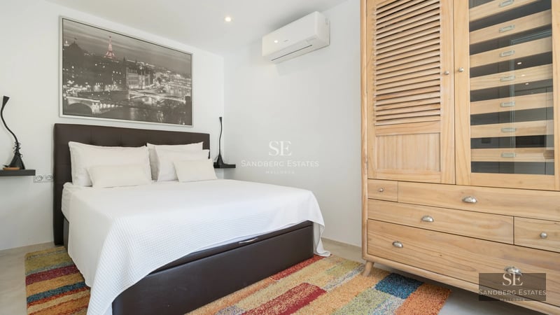 Spacious living room with panoramic windows, sea view, light wood floors and modern furnishings in neutral tones.