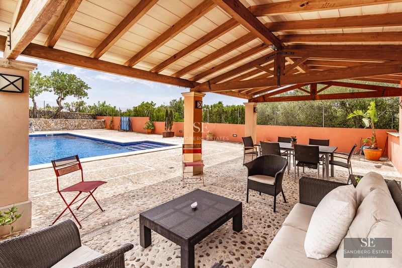 View of modern villa with infinity pool, lush garden, and sleek architectural design. Expansive glass windows and terraces.