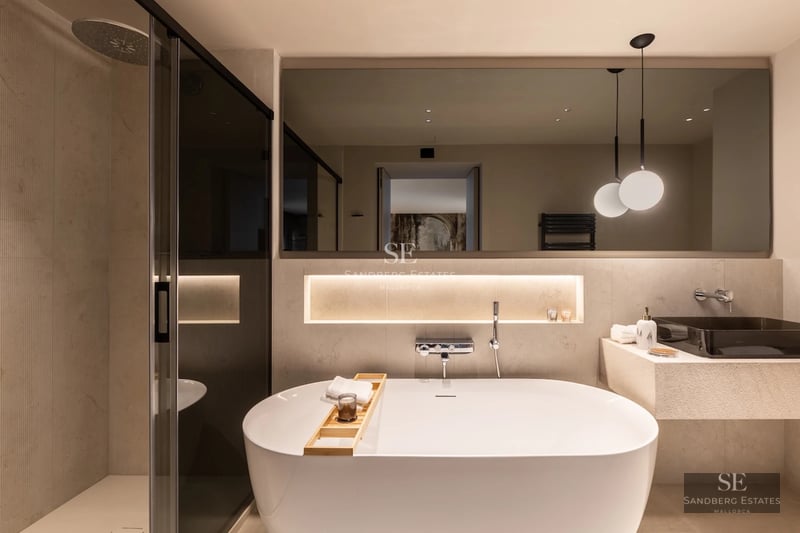 Spacious balcony with sea view. Glass railing, grey tile floor, and modern furniture. Soft ambient lighting.