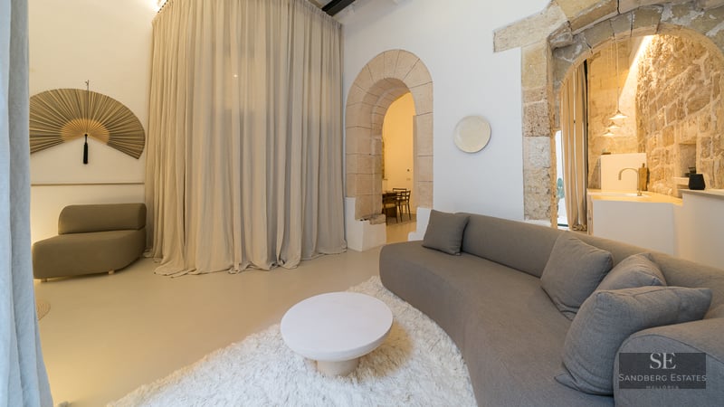 Contemporary living room featuring a curved grey sofa, white shag rug, and historic natural stone arches.