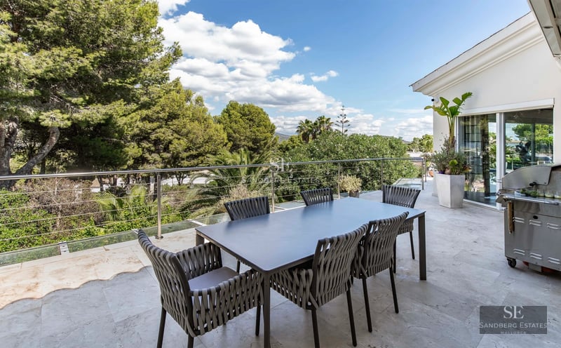 View of a luxury villa featuring an infinity pool, terrace with modern furniture, and lush greenery. Sleek and contemporary architectural design.