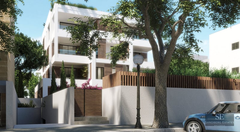 Modern white four-story apartment building with wood accents, large balconies, and lush greenery seen from street.