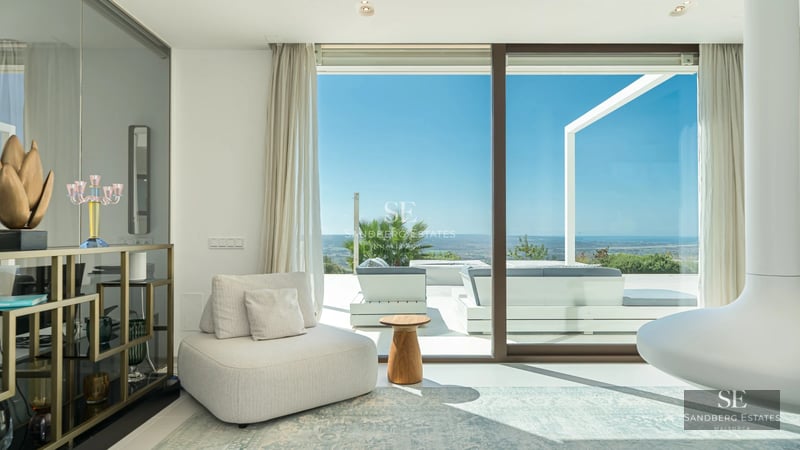 Bright living room with sea view through panoramic windows, light wood floors and modern furniture in neutral tones. Elegant design and panoramic views.