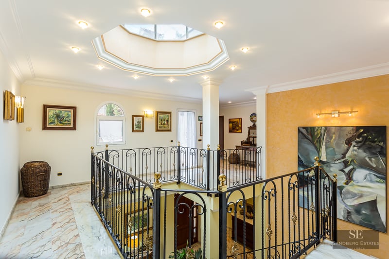Interior landing with marble floors, a wrought iron railing, and an octagonal skylight in the ceiling.