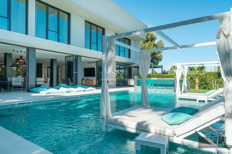 Spacious living room with sea view, white sofas, modern rug and minimalist coffee table. Natural and elegant lighting.