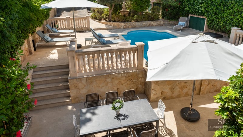 Exterior view of a modern villa featuring an infinity pool, lush garden, and minimalist architectural design.