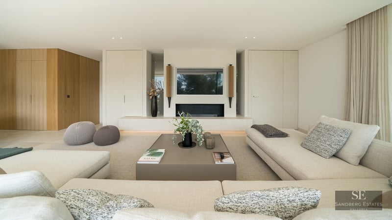 Spacious living room featuring beige sofas, an integrated fireplace, and a modern coffee table in neutral tones.