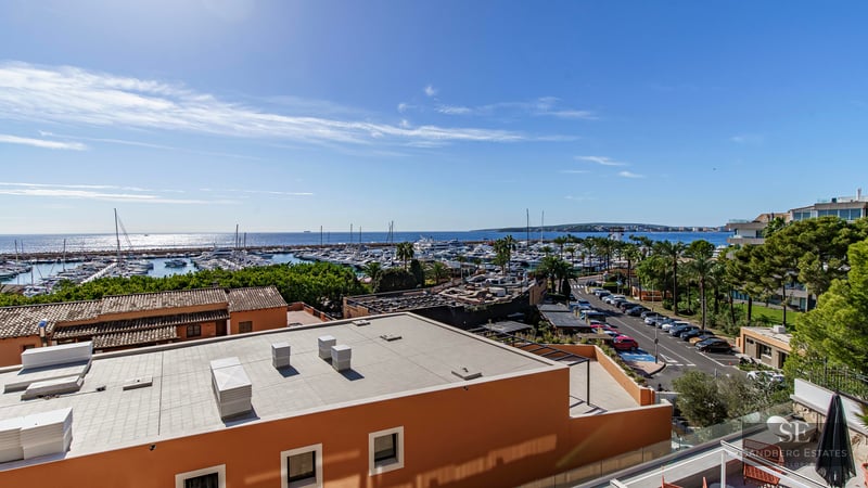 Elevated view overlooking a marina with yachts and the Mediterranean sea under a clear blue sky.