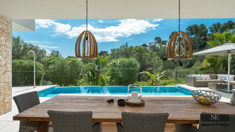 Exterior of a modern villa with a pool, outdoor living area, and lush greenery. Minimalist and elegant design.