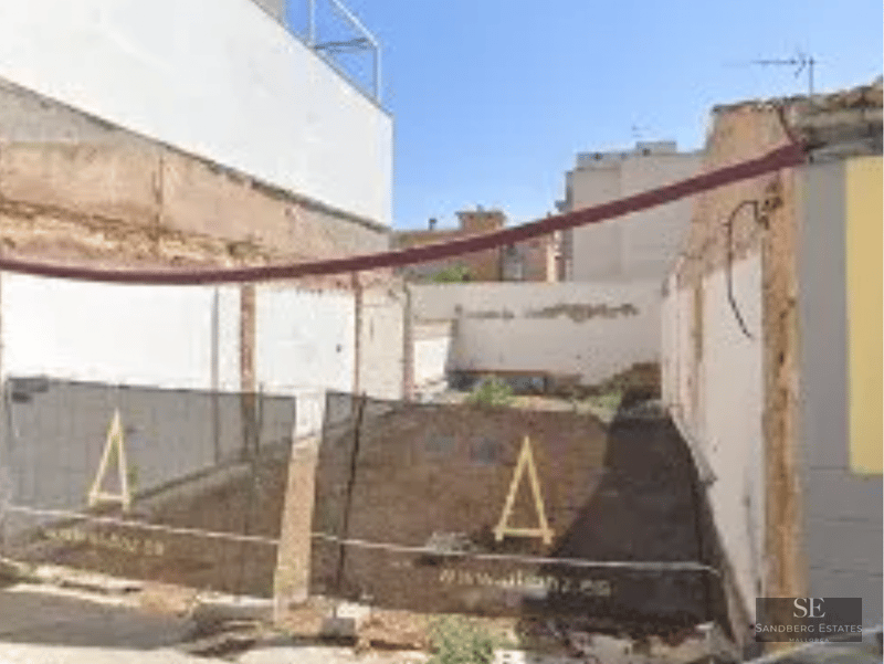 View of a construction site with safety fencing and visible white perimeter walls.