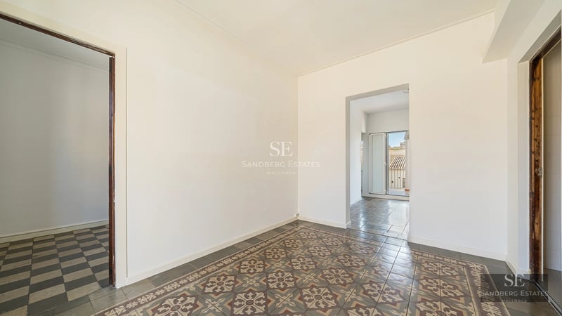 View of a private pool with sun loungers and umbrellas, surrounded by lush greenery and a modern house with large windows.