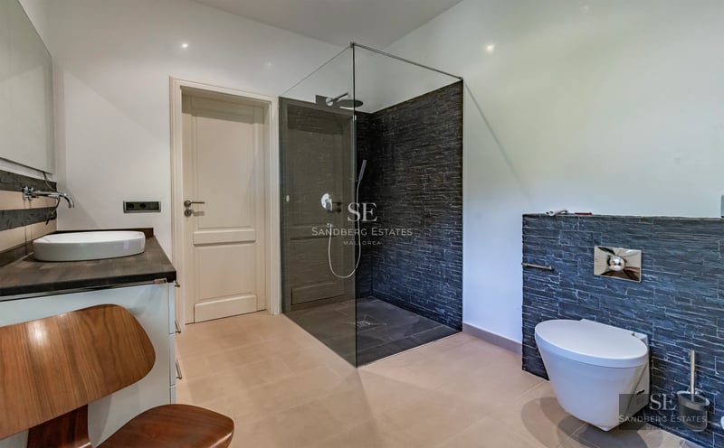 View of infinity pool with terrace, sun loungers, and lush garden. Modern architecture and elegant design with large glass windows.