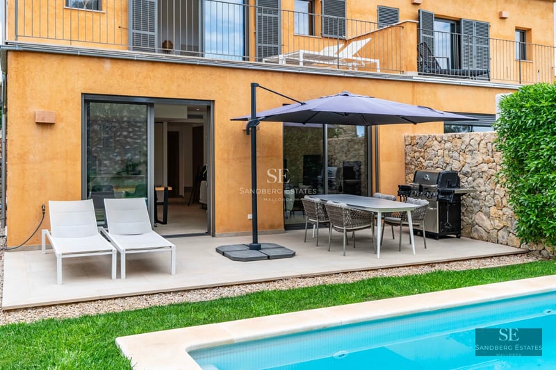 Exterior view of a luxurious, modern villa featuring a pool, manicured garden, and expansive terraces. Minimalist and bright architecture.