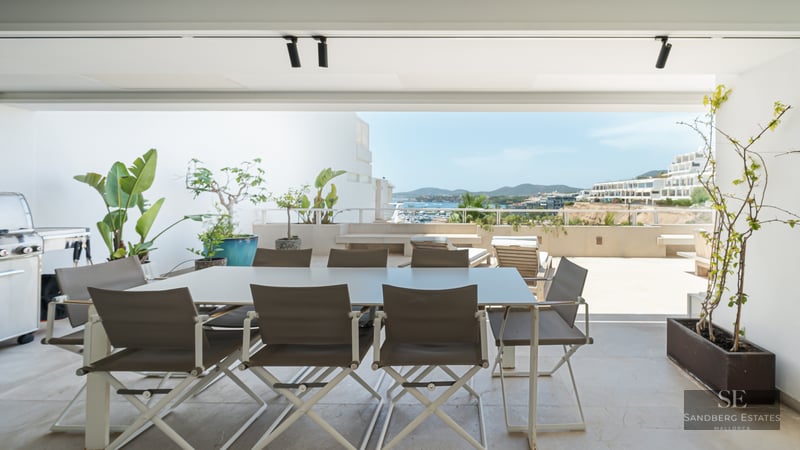 Modern terrace with outdoor dining area, BBQ, and panoramic views of the coastal town and sea.