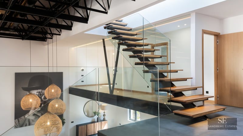 Wood and glass staircase with black metal structure and woven pendant lights in a modern interior.