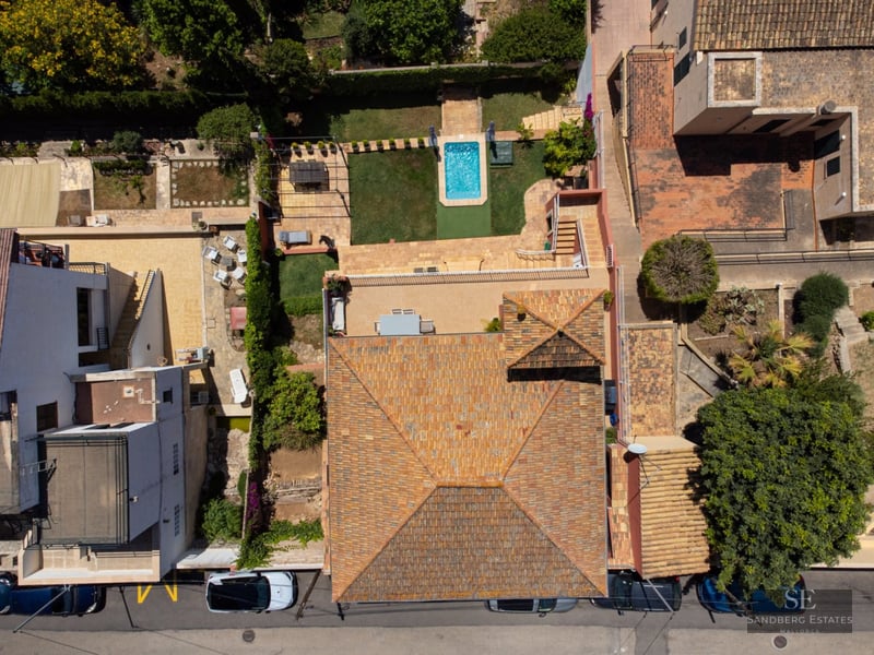 Aerial top-down view of a Mediterranean house with a tiled roof, small swimming pool, and landscaped garden.