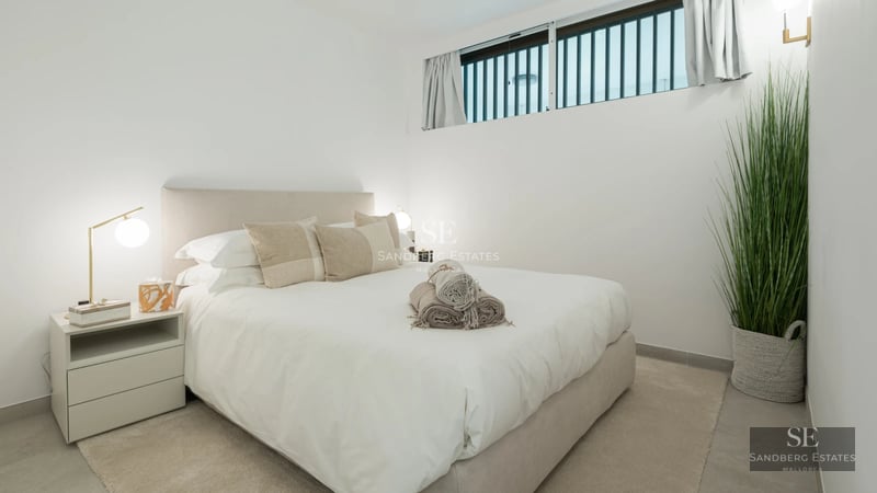 Panoramic view from a balcony featuring wood flooring, glass railing and modern furniture overlooking the sea. Natural lighting.