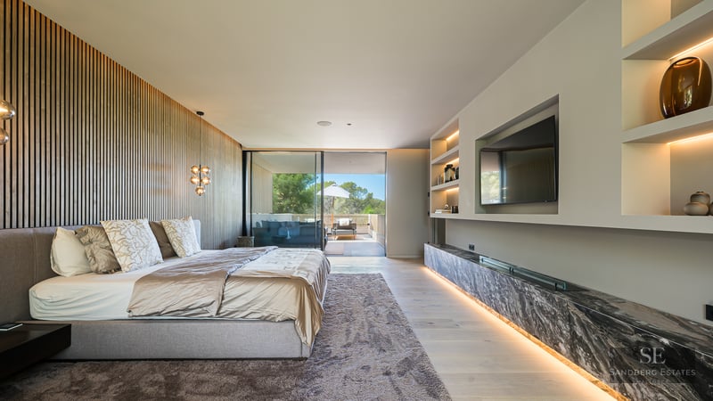 Modern master bedroom featuring a wooden slat wall, large bed, marble accents, and sliding doors to a terrace.