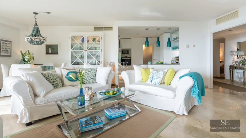 Spacious living room with panoramic windows, sea view, modern furniture, neutral color palette, and abundant natural light.