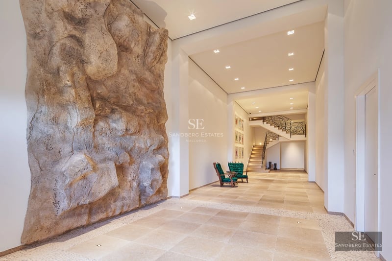 View of an elegant villa with a pool, lush garden, and modern architectural design. Stone details and large windows.