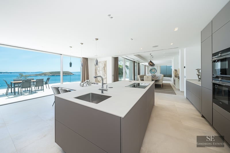 Minimalist kitchen island facing a terrace with expansive ocean views and a distant island.