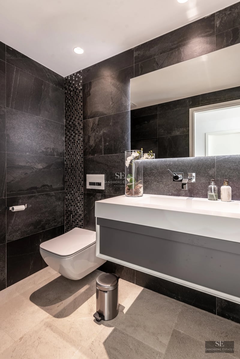 Spacious living room with large windows, leather sofas, modern rug and panoramic views. Warm and elegant lighting.