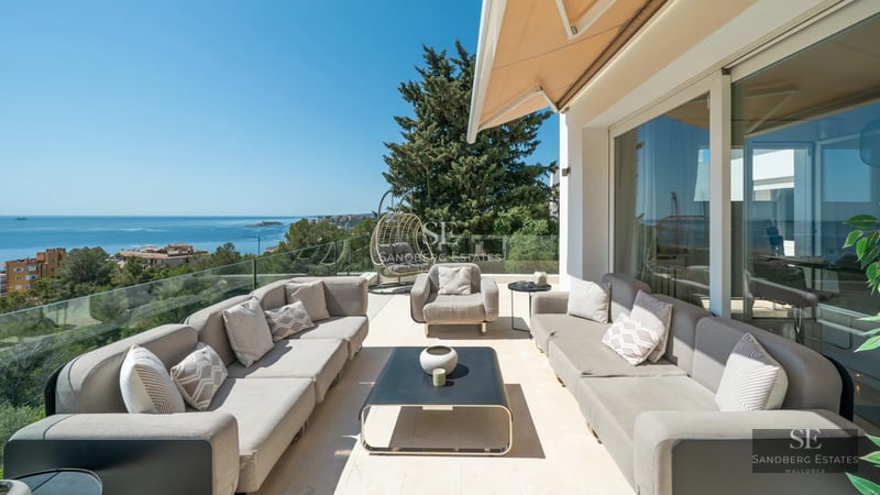 View of a modern swimming pool with sun loungers, surrounded by greenery and with a contemporary house in the background. Minimalist architectural design.