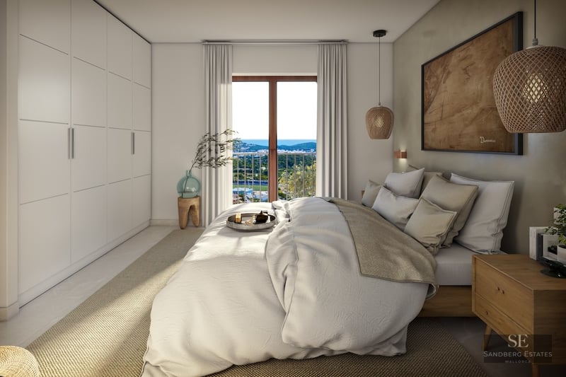 Elegant master bedroom with white linens, built-in wardrobes, and a balcony overlooking a coastal landscape.
