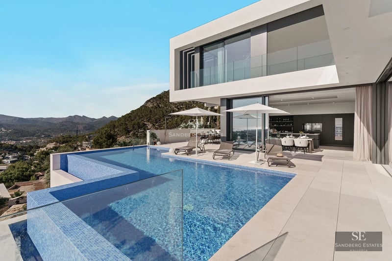 Exterior view of a modern villa featuring a pool, manicured garden, and expansive terraces. Minimalist architectural design with clean lines.