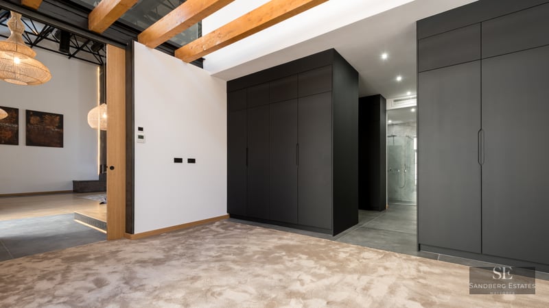 Dressing area featuring large black cabinets, exposed wooden ceiling beams, and plush beige carpeting.