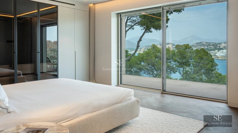 Expansive pool surrounded by lush greenery. Modern architecture with large windows and a sunny terrace. Luxurious ambiance.