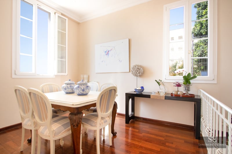 Bright dining room with white table, striped chairs, hardwood floors, and large windows.